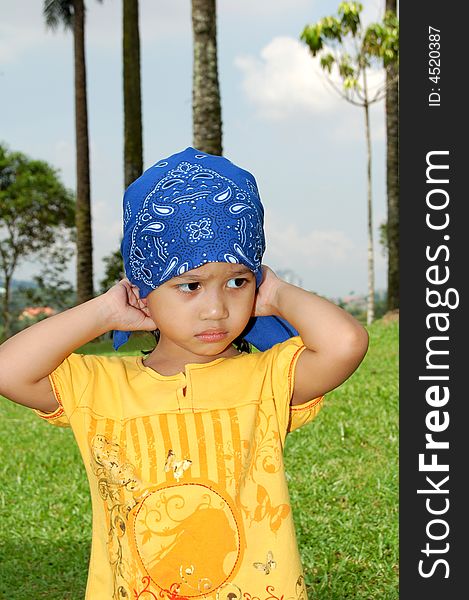 A little girl wearing bandana covering her head at the park. A little girl wearing bandana covering her head at the park.