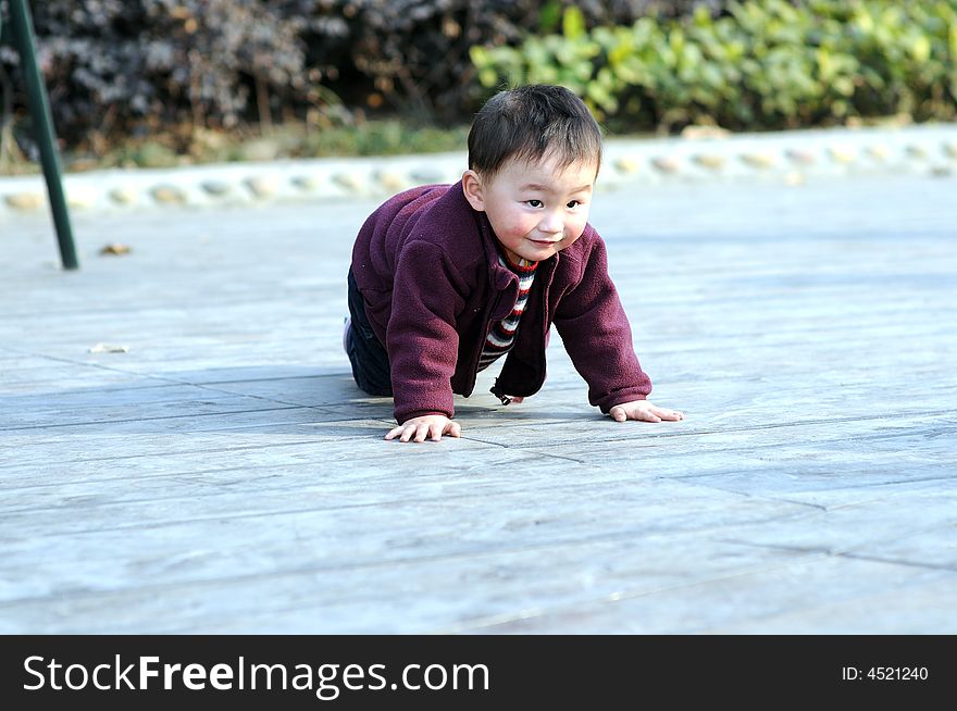 A little boy is climbing on the floor.