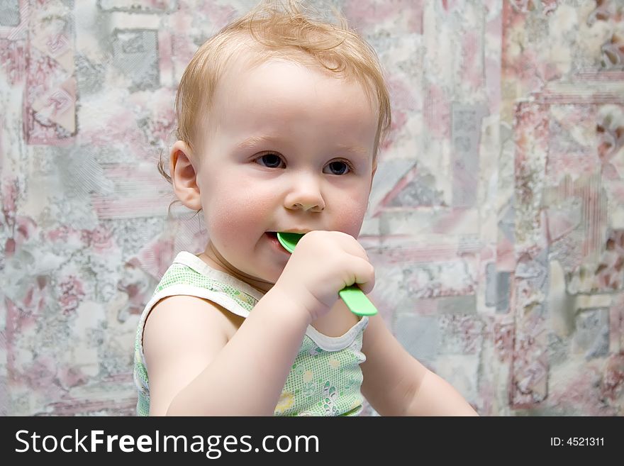 Baby with green spoon in hands. Baby with green spoon in hands