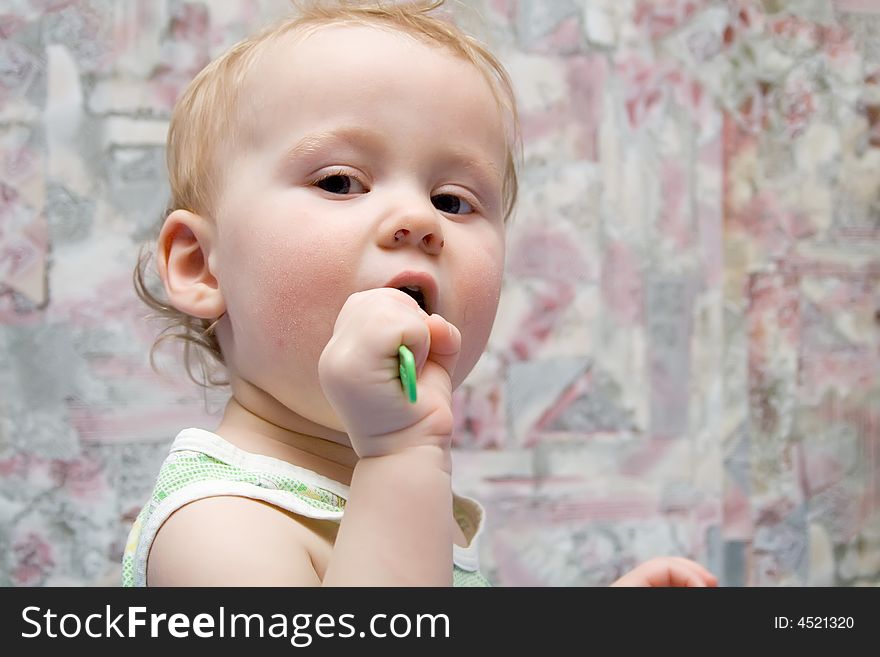 Baby with green spoon in hands. Baby with green spoon in hands