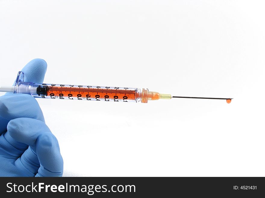 Gloved hand holding red liquid filled syringe with needle. Gloved hand holding red liquid filled syringe with needle