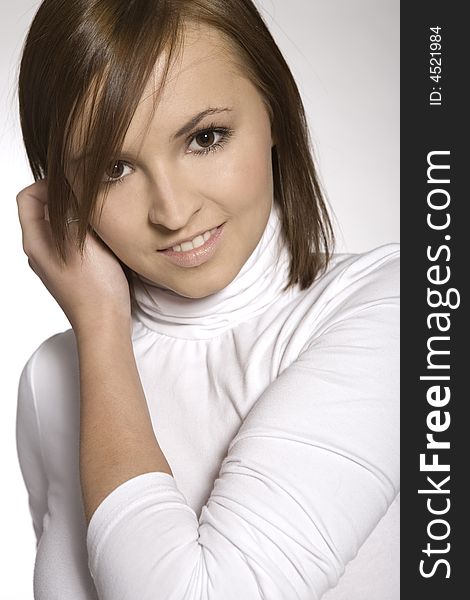 Close-up of beautiful brunette young girl wearing white blouse on light background