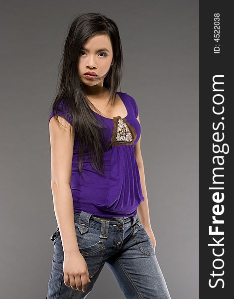 Studio shot of beautiful Asian model wearing purple blouse and jeans