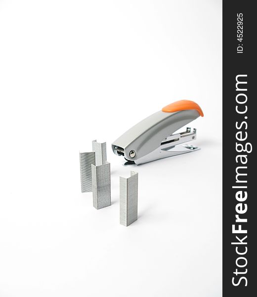 Silver and orange Stapler with staples on white background