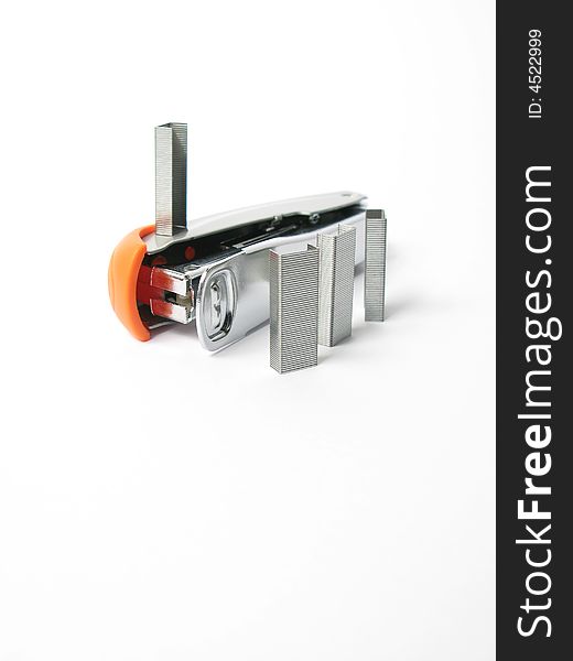 Silver and orange Stapler with staples on white background