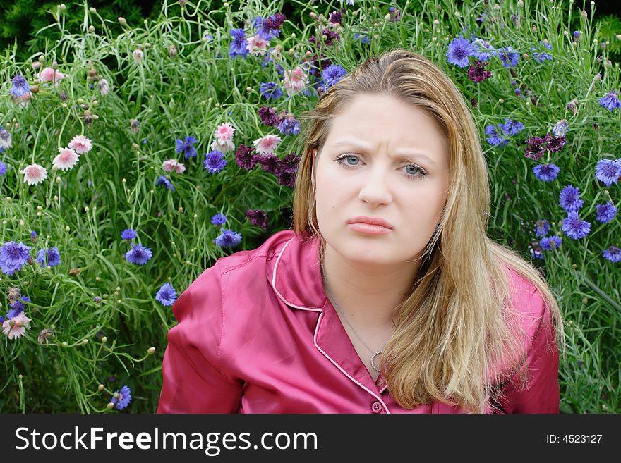 Humourous portrait of a woman pouting in a Summer garden in full bloom. Humourous portrait of a woman pouting in a Summer garden in full bloom