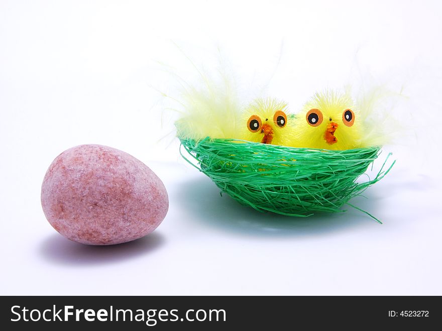 Two easter chicks in a nest with an egg outside