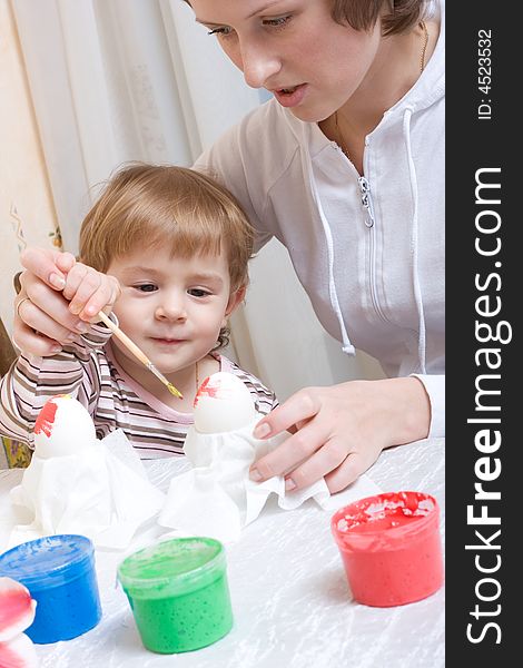 Little child painting eggs before easter