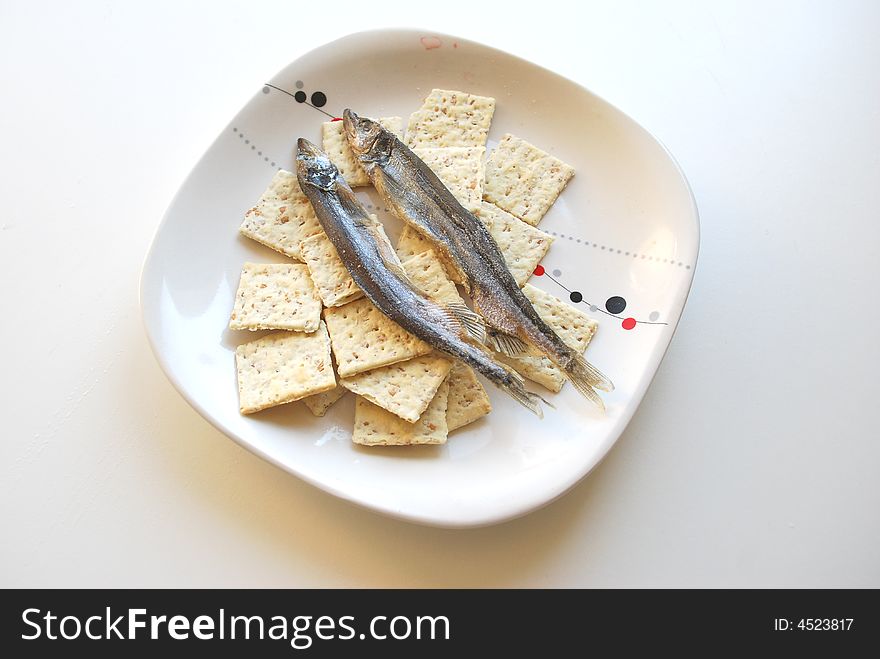 Dry small fishes and crackers on a dish. Dry small fishes and crackers on a dish.