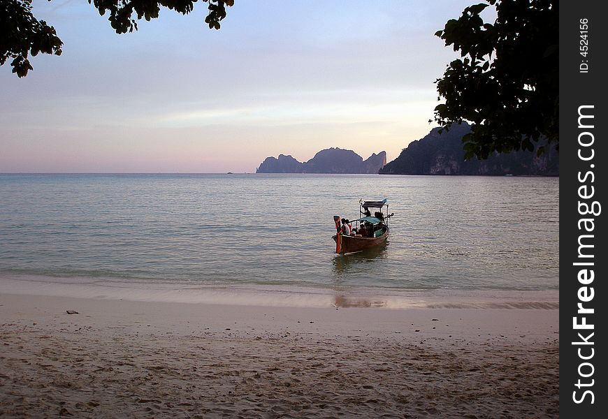 Longtail boat coming ashore on soft, dreamy evening.  Koh Phi Phi Island, Thailand. Longtail boat coming ashore on soft, dreamy evening.  Koh Phi Phi Island, Thailand