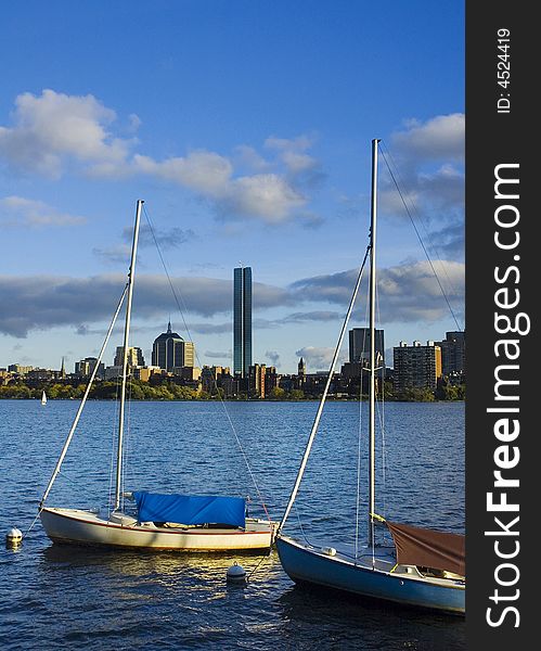 Two sailboats moored on the Cambridge side of the Charles River with the Boston skyline in the background. Two sailboats moored on the Cambridge side of the Charles River with the Boston skyline in the background.