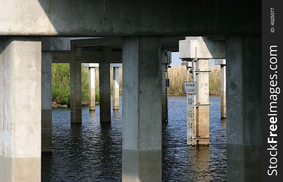 Highway bridge over the Saint John's River, Florida. Shot from below showing cluster of support pilings, river and underside of roadway. Center of focus is on the river depth gauge attached to one of the support posts