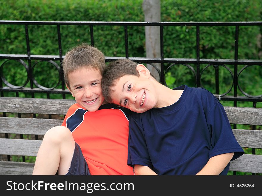 Brothers Smiling Sitting on a Park Bench