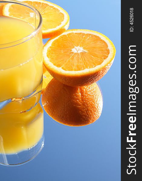 Glass of orange juice and incised orange on blue background. Glass of orange juice and incised orange on blue background