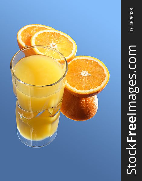 Glass of orange juice and incised orange on blue background. Glass of orange juice and incised orange on blue background