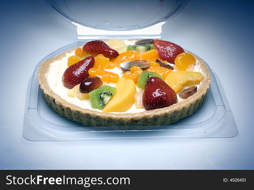A fruit pie in a plastic transparent box on a blue background