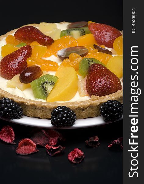 A fruit pie on a white plate on a black background