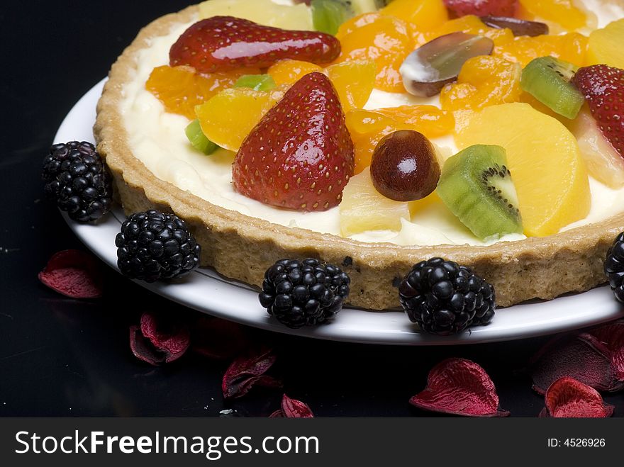 A fruit pie on a white plate on a black background
