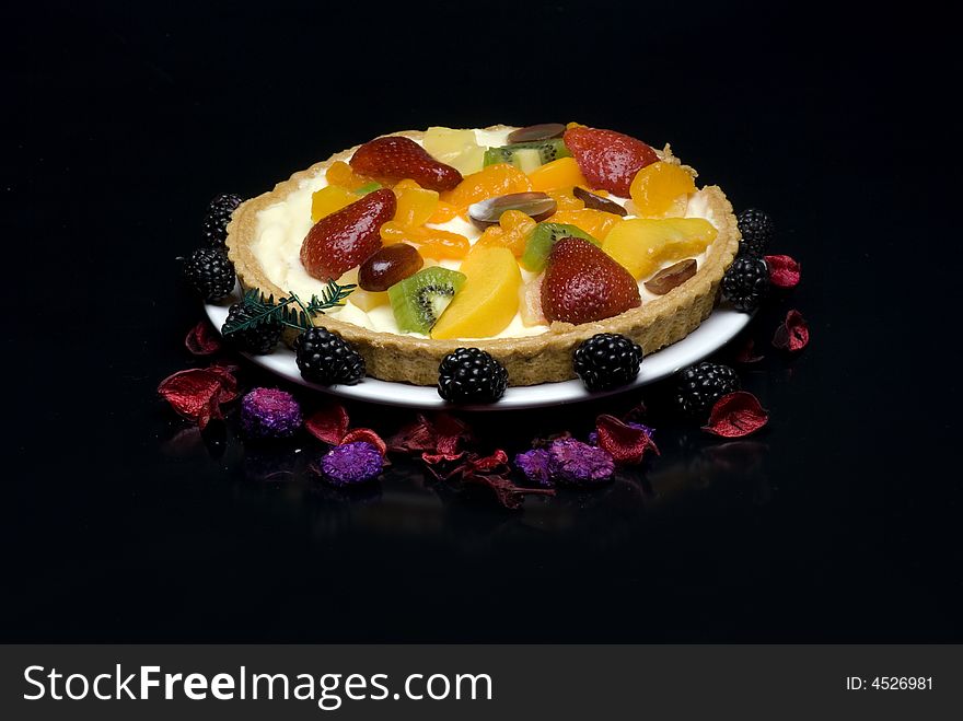 A fruit pie on a white plate on a black background