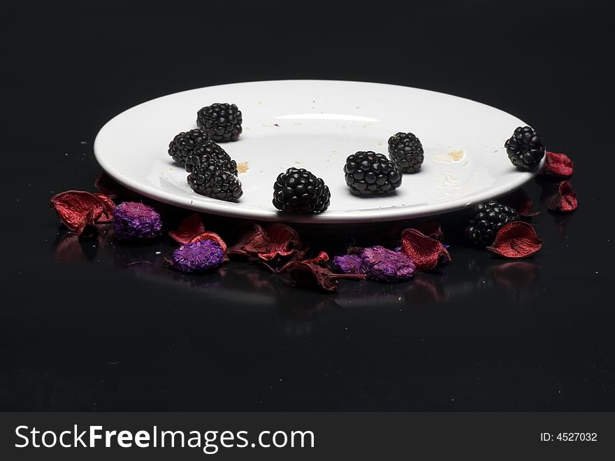 Fruits and small pieces of croissant on a plate isolated on black background