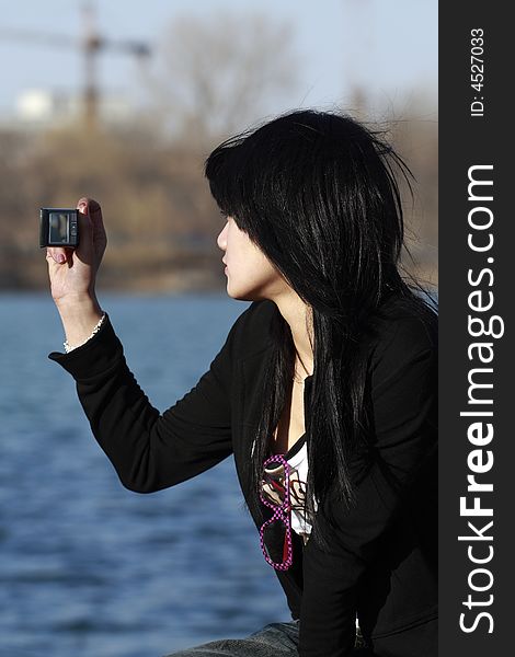 A beautiful Chinese girl shoots the beautiful scenery with the mobile phone happily. A beautiful Chinese girl shoots the beautiful scenery with the mobile phone happily.