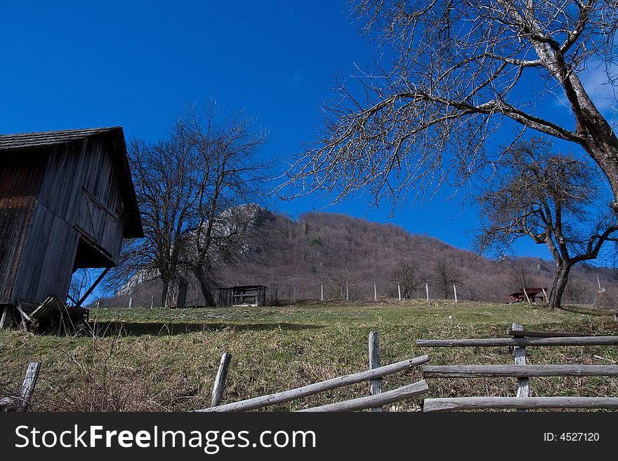 Old wooden hut in the yard and trees behind the fence. Old wooden hut in the yard and trees behind the fence