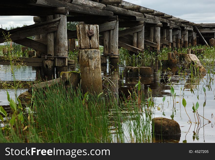 Old wooden bridge, green grass, reflections in water