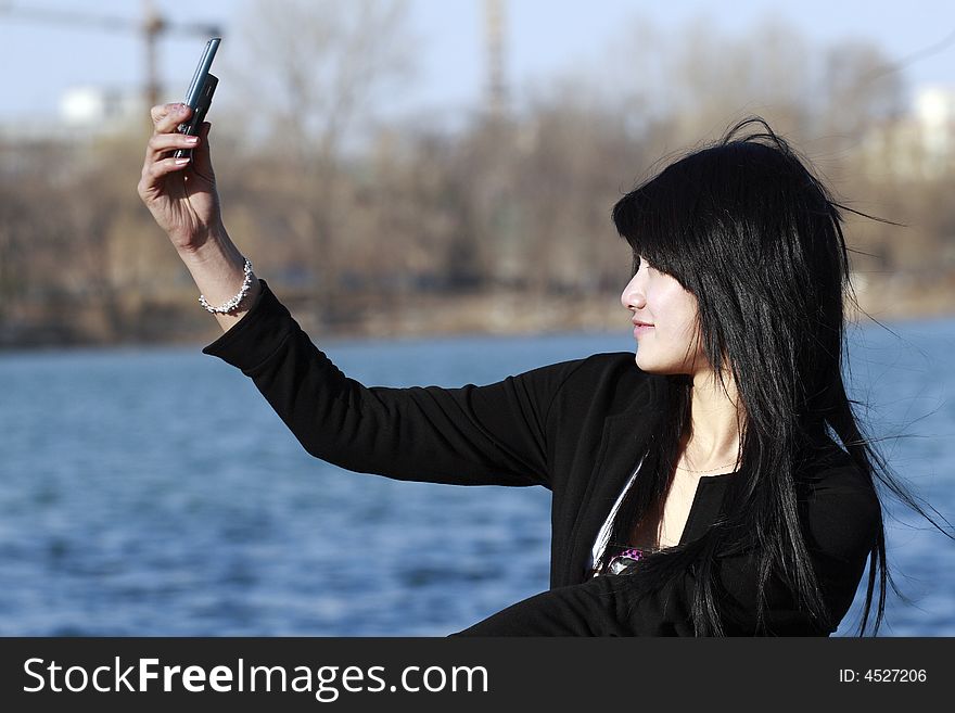 A beautiful Chinese girl is shooting herself with the mobile phone happily. A beautiful Chinese girl is shooting herself with the mobile phone happily.