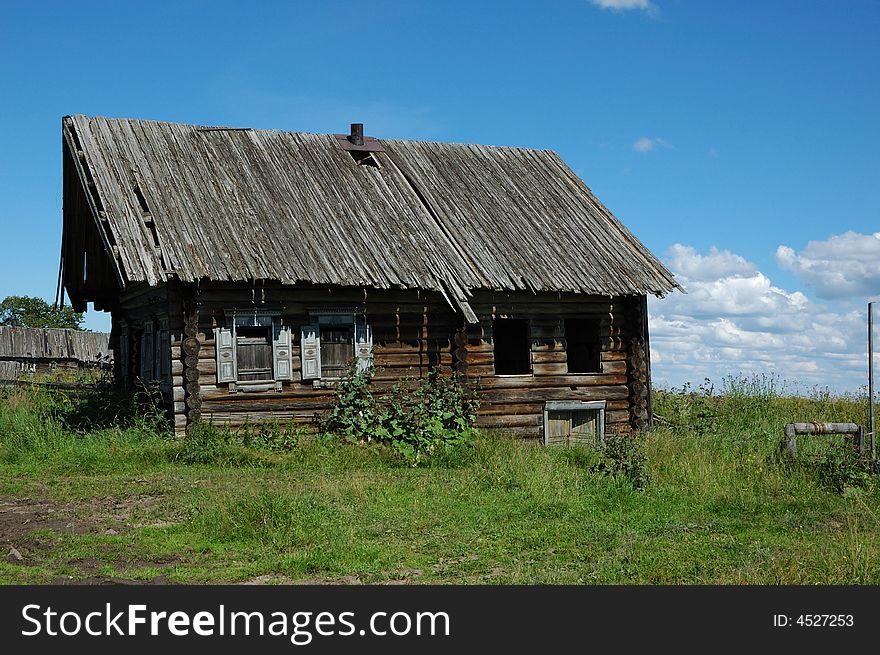 Single destroyed wooden house in field with old wooden draw-well. Single destroyed wooden house in field with old wooden draw-well