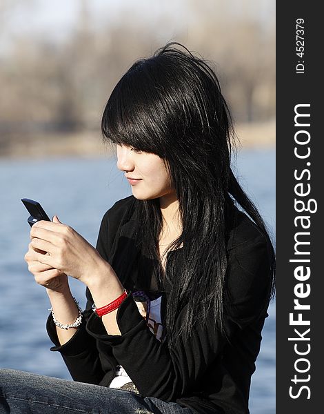 This Chinese girl is looking over the information in her mobile phone. This Chinese girl is looking over the information in her mobile phone.