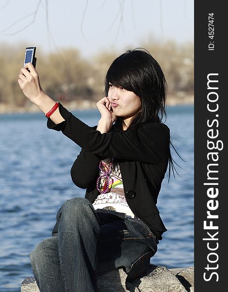 A beautiful Chinese girl shoots herself with the mobile phone happily.The appearance of making faces is very lovely. A beautiful Chinese girl shoots herself with the mobile phone happily.The appearance of making faces is very lovely.