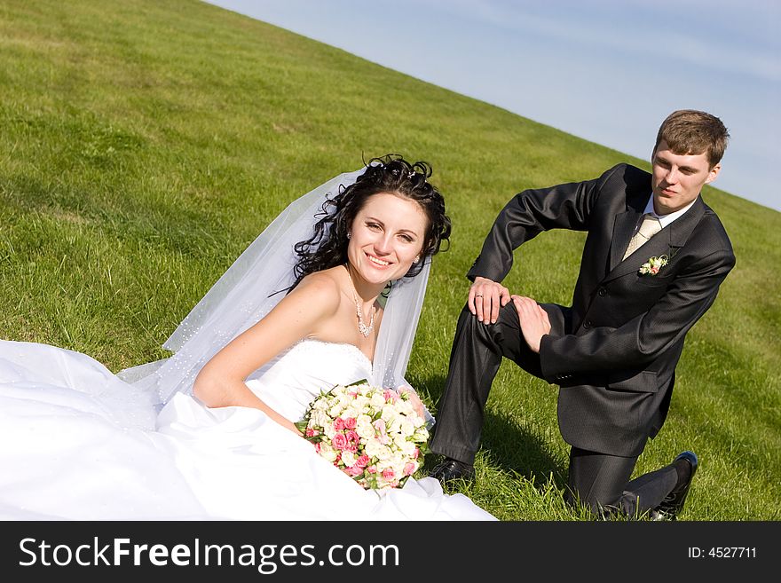 Bride and groom sit on a green grass. Bride and groom sit on a green grass