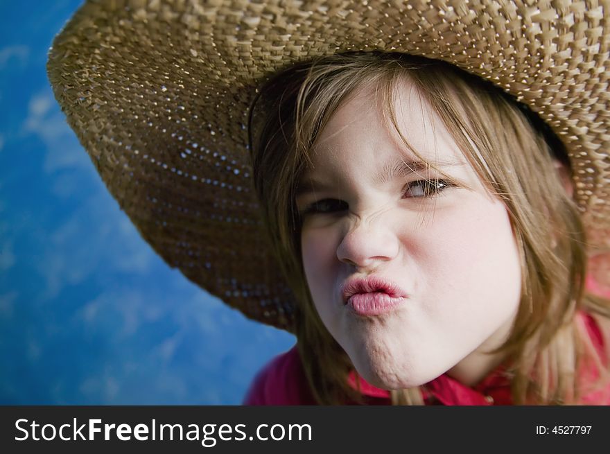 Little girl wearing a straw cowboy hat makes a funny face. Little girl wearing a straw cowboy hat makes a funny face