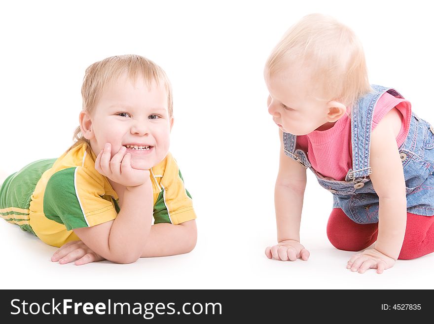 A small girl looking at the smiling boy, the both are on the floor. A small girl looking at the smiling boy, the both are on the floor