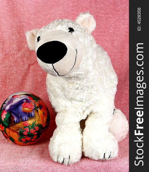 White teddy bear and ball on pink background