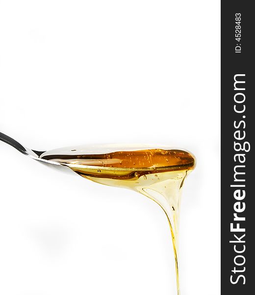 Honey on a spoon over a white background