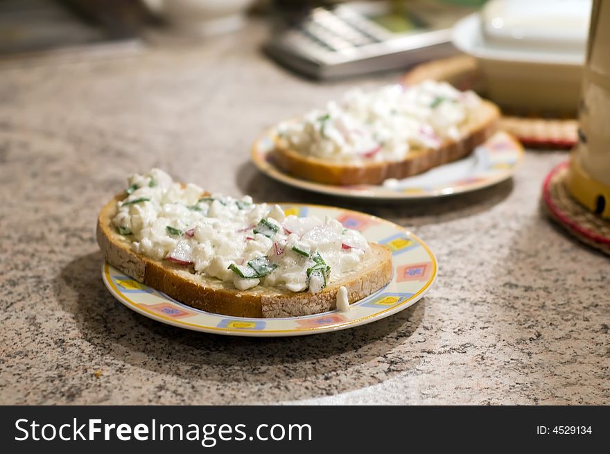 Two slices of bread with grained white cheese, radish and chive