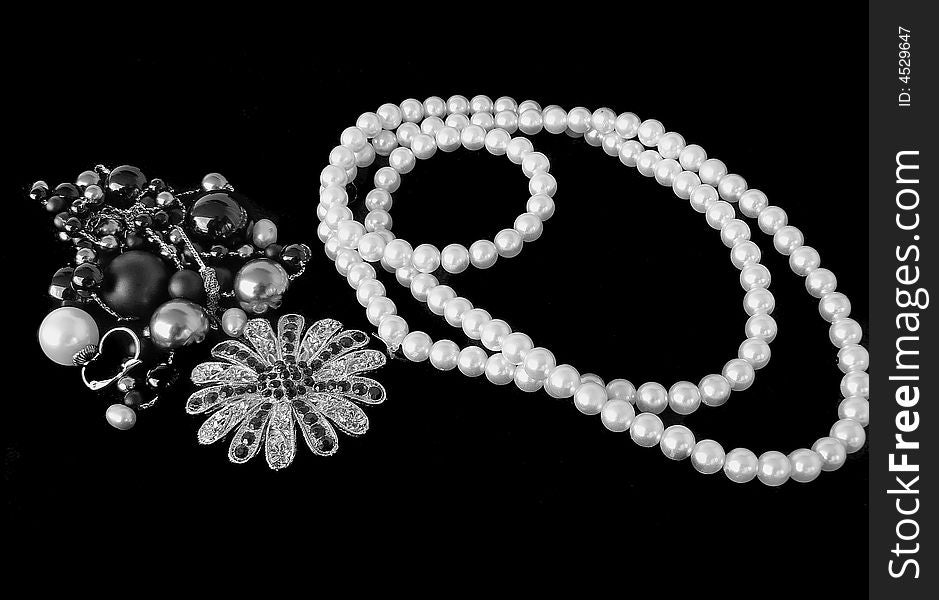 String of pearls and brooches on black background. String of pearls and brooches on black background.