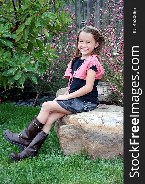 Little girl sitting on a rock, being silly. Little girl sitting on a rock, being silly