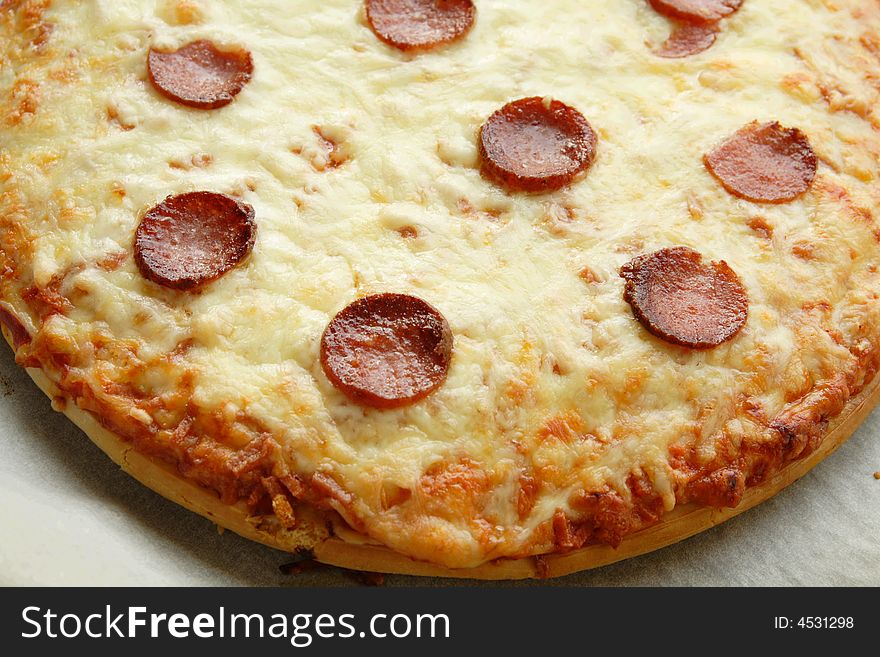 Big pan pizza with lots of cheese and salami slices