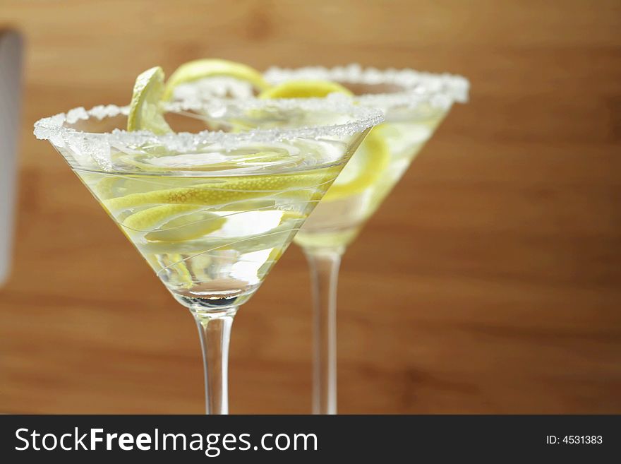 Martini drinks with sugar crust and lemon closeup with wood colored background