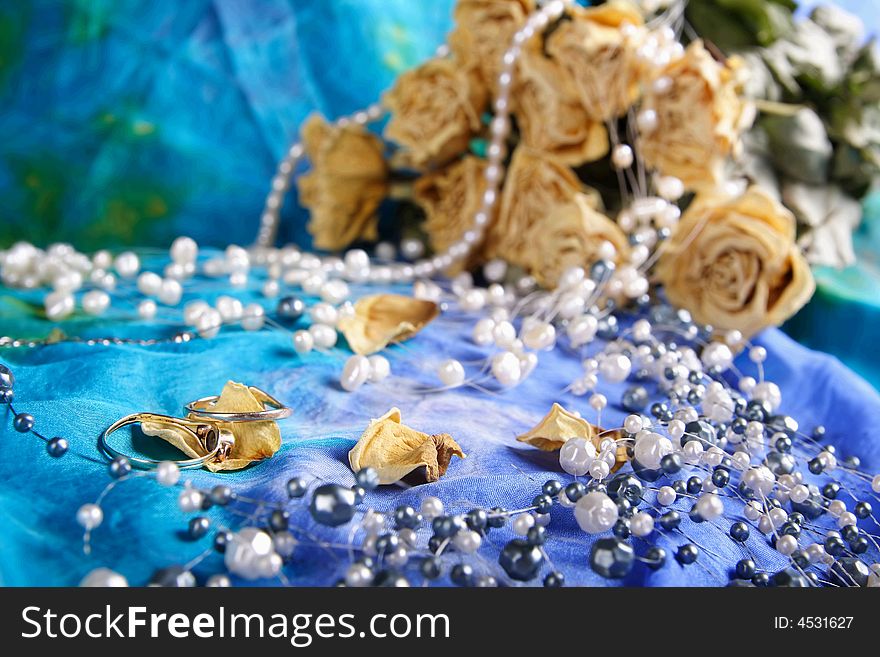 Dried roses and pearls with rings in foreground