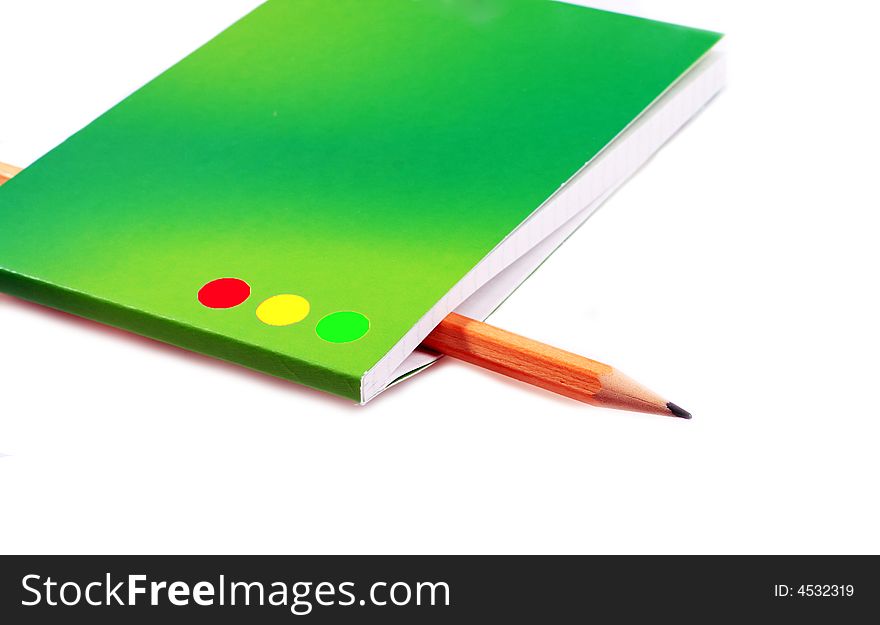 The pencil is inserted into a green notebook. The pencil is inserted into a green notebook