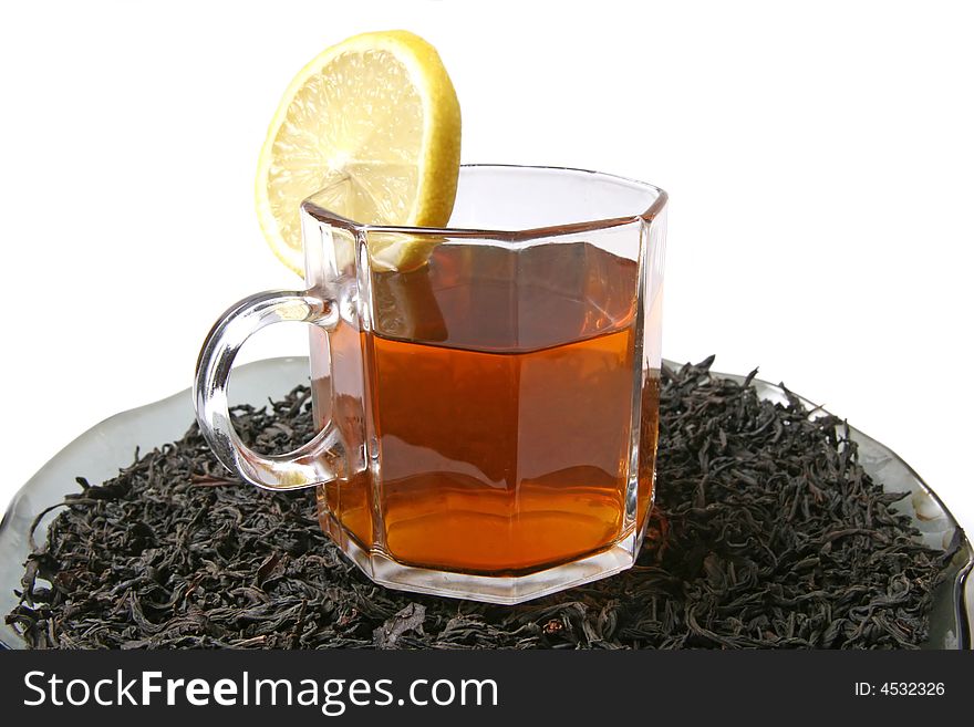 A cup of tea with a lemon on a black tea leaves