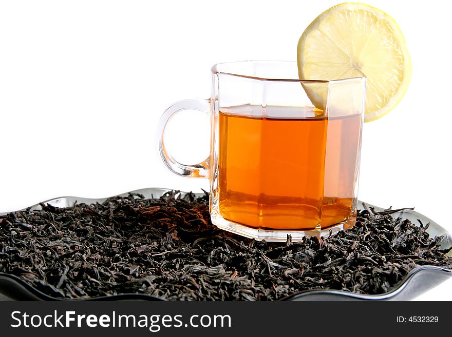 A cup of tea with a lemon on a black tea leaves