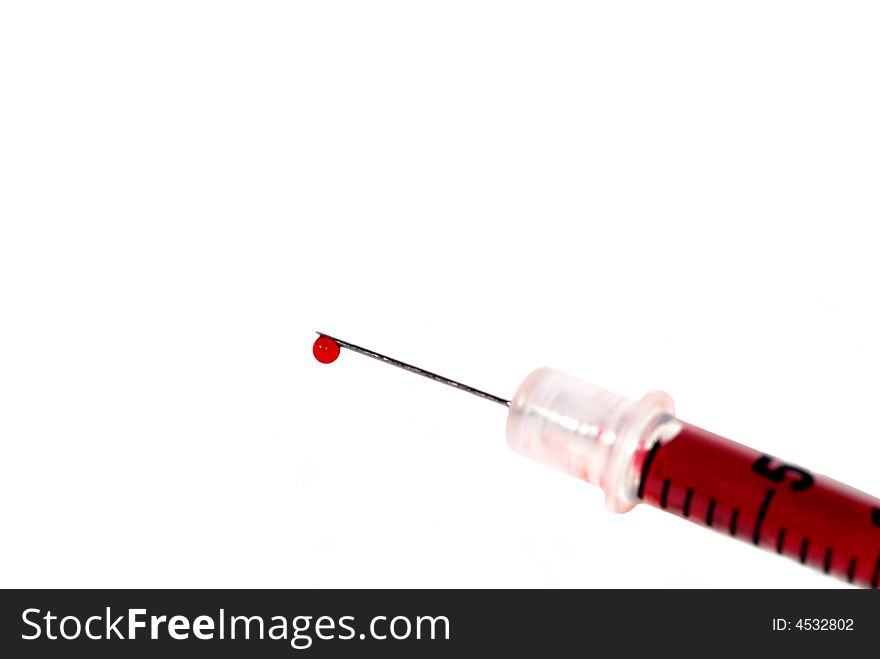 A syringe loaded with red liquid, a drop on end of needle-isolated on white. A syringe loaded with red liquid, a drop on end of needle-isolated on white.