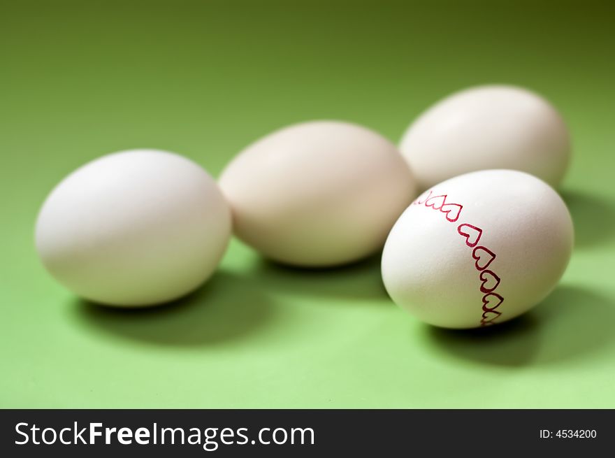 Four easter eggs painted with heart shape on green background