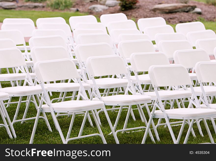 White chairs arranged and setup for a wedding ceremony. White chairs arranged and setup for a wedding ceremony