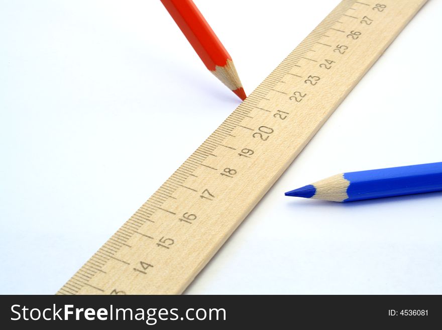 Two coloured pencils and wooden ruler on white background. Two coloured pencils and wooden ruler on white background