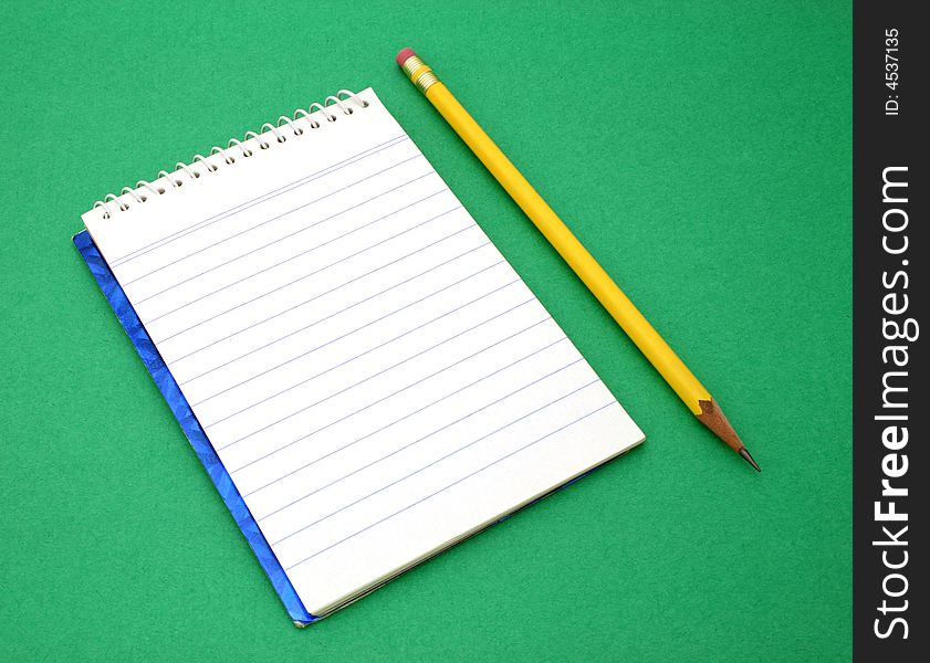 Yellow pen besides an open notebook on a green surface. Yellow pen besides an open notebook on a green surface